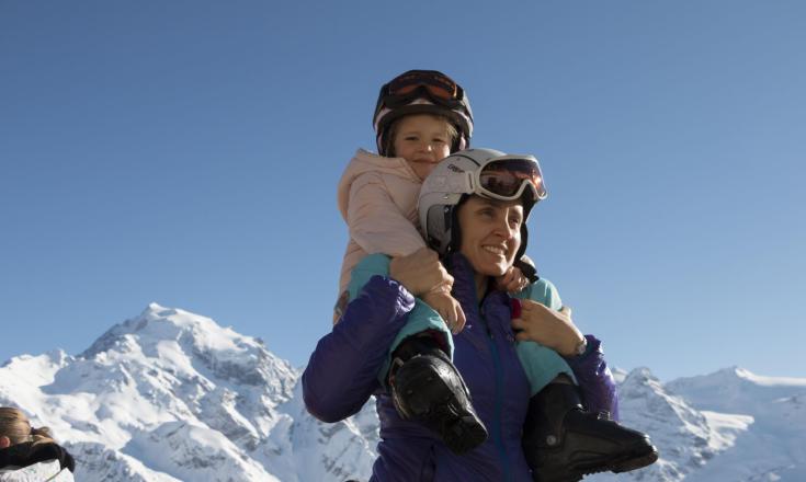 Una donna porta una bambina sulle spalle