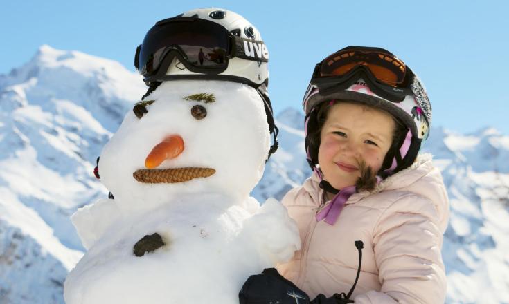 Una bambina e un pupazzo di neve